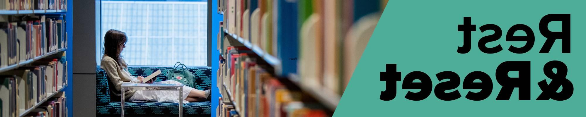 Image of a person reading at the library while seated on a couch; book stacks on either side of the forefront. Image says "rest & reset"